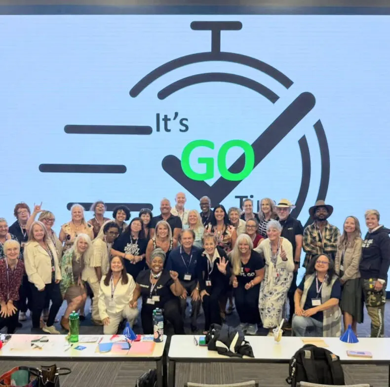 Group photo of participants at a training event in front of an “It’s Go Time” display.