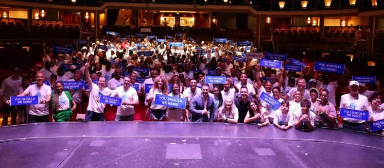 DreamTrips members holding “You Should Be Here” signs during the 20th anniversary relaunch cruise community event