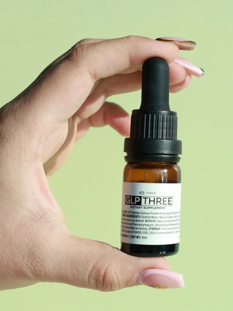 Hand holding GLP THREE™ dietary supplement bottle, from THREE International