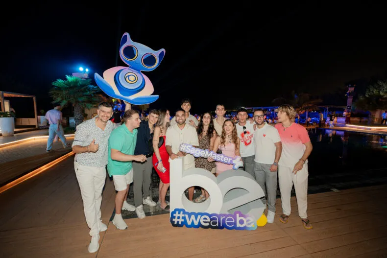 Group of BE affiliates celebrating at the Dubai Sapphire Retreat nighttime event holding #SageMaster and #wearebe signs.