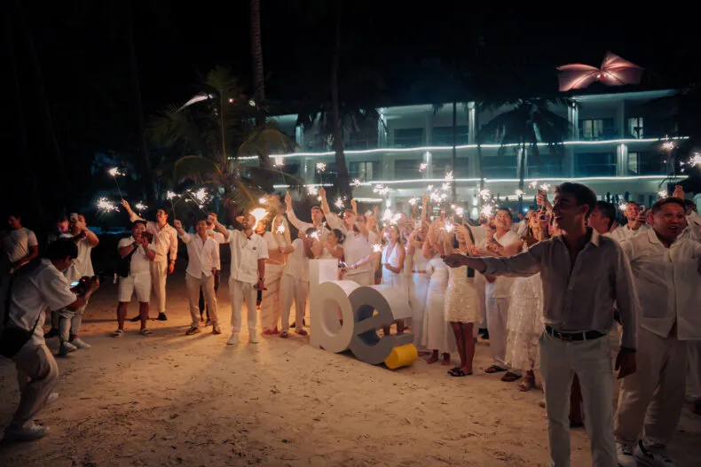 Leaders at the BE Leadership Retreat holding sparklers during the all-white celebration on the beach