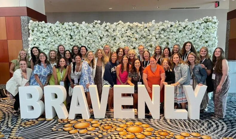 Bravenly Global leaders taking a group photo with BRAVENLY letters at the Summer Success Summit