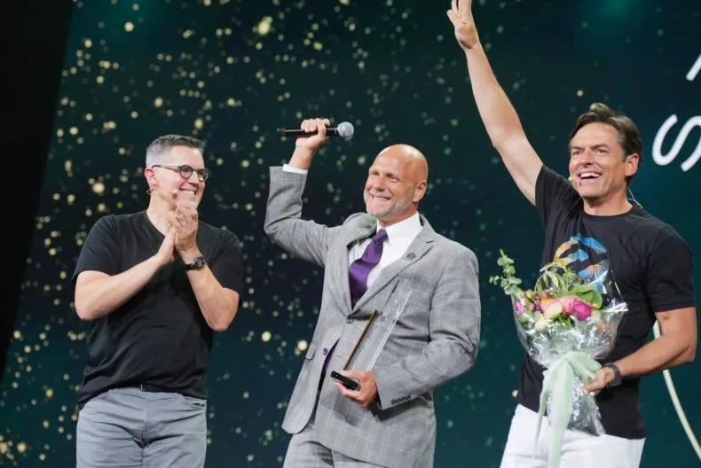 Brent Palmer celebrates on stage with Partner.Co executives after winning the 2025 Vision Award.