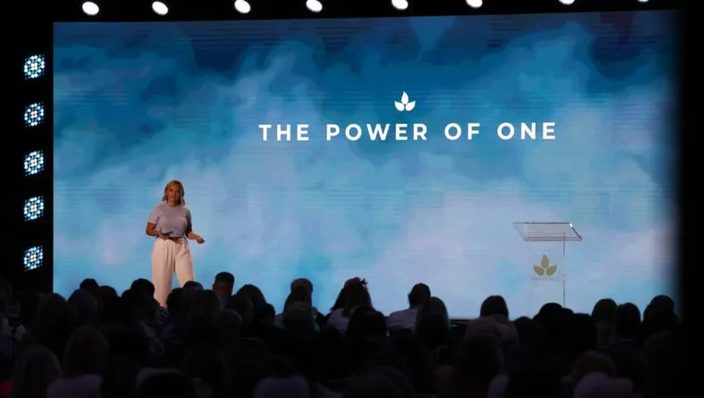 Brittany Beck delivering a keynote speech on stage at Bravenly Global Summer Success Summit 2025