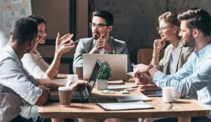 business team discussing ideas around a table with laptops and documents