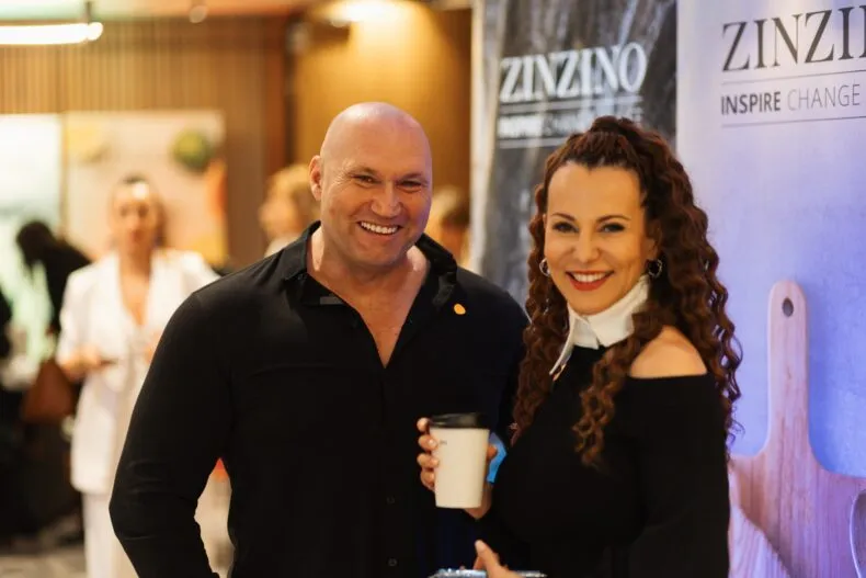 Csapó Dorina, Zinzino Crown Leader, smiling with a colleague in front of a Zinzino banner, holding a coffee cup.