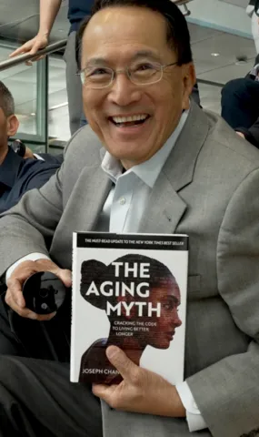 Dr. Joseph Chang holding The Aging Myth book during Nu Skin relaunch announcement