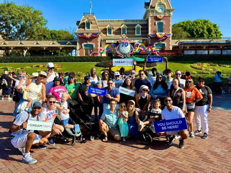 DreamTrips members posing in front of the Disneyland railroad station holding DreamTrips signs