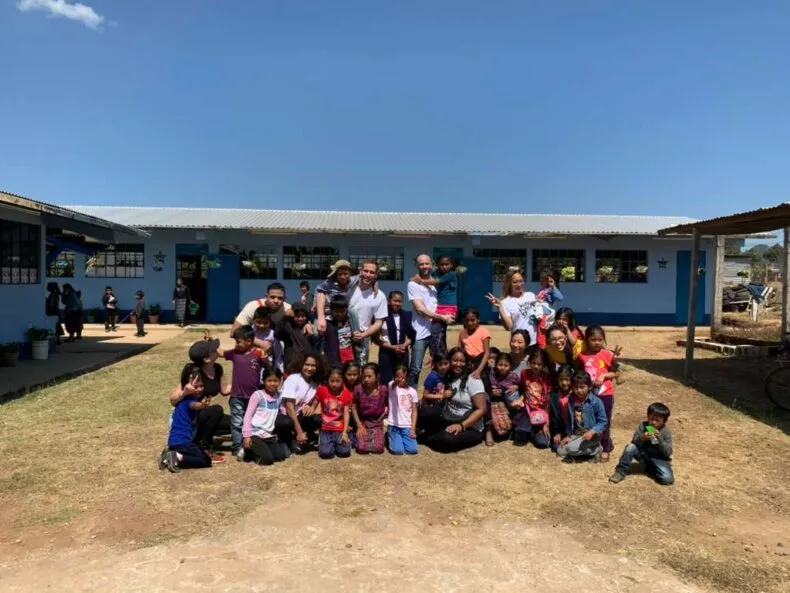 DreamTrips volunteers and local students posing together in front of a completed Bottle School