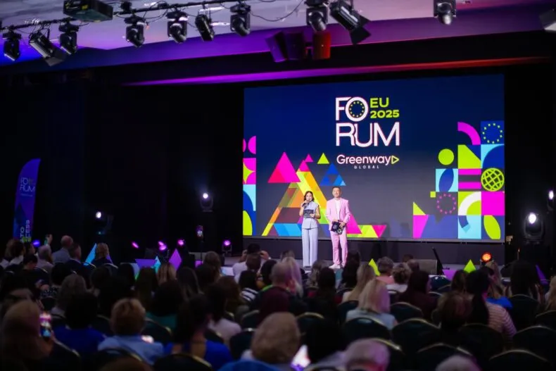 Hosts on stage at Greenway Global Croatia Forum 2025 with colorful branding and audience in attendance.