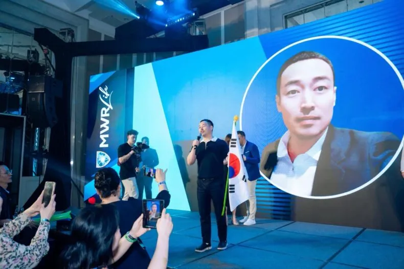 Heo Je-won speaking on stage at an MWR Life event in South Korea