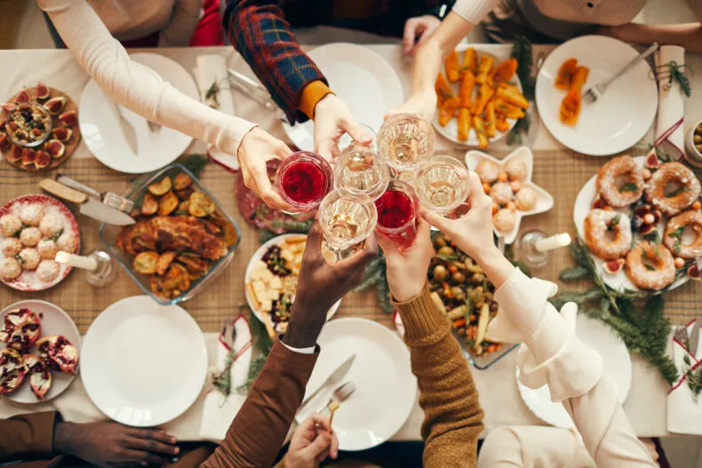 People raising glasses at a holiday dinner table during a festive gathering