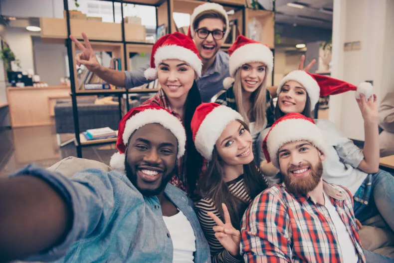 Group of friends wearing Santa hats taking a cheerful holiday selfie