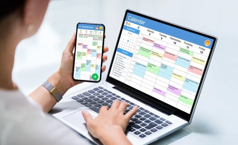 Person planning a holiday schedule using a laptop and smartphone calendar