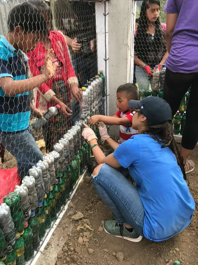 Volunteers and children building an eco-brick wall for a Bottle School in Guatemala