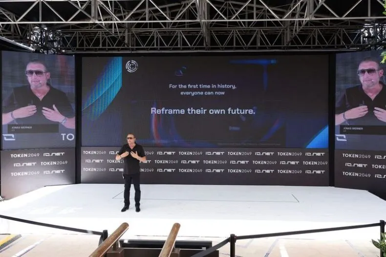 Jonas Eric Werner onstage delivering keynote at TOKEN2049 with the phrase "Reframe their own future" behind him