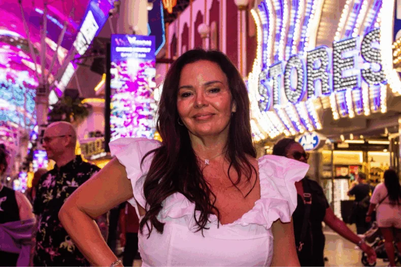 Kelly Tolar, DreamTrips leader, pictured on a vibrant downtown street at night — representing travel, empowerment, and leadership through lifestyle freedom.