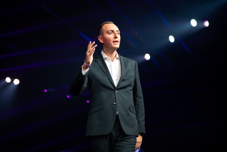Kris Kamras speaking on stage at a major Zinzino event