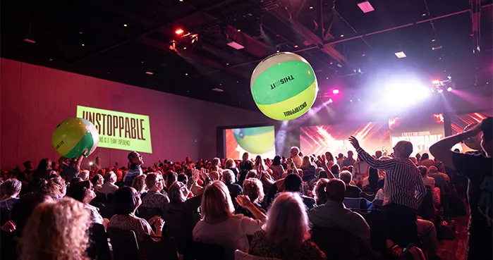 UNSTOPPABLE Convention 2026 audience celebrating with beach balls and stage lighting