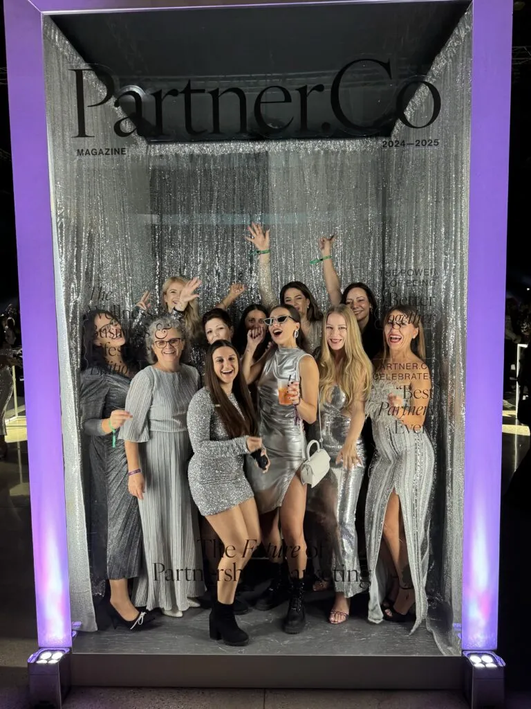 Lorena Gabor and team posing in a Partner.Co magazine frame at a celebration event