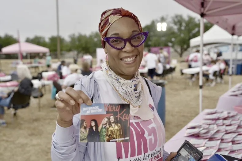 Smiling Mary Kay MK5K 2026 participant holding a Mary Kay campaign card at the fundraising event