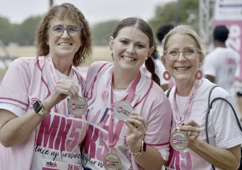 Three Mary Kay MK5K 2026 finishers smiling and displaying their race medals