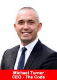 Michael Turner, CEO of The Code, in a formal suit portrait with a white background