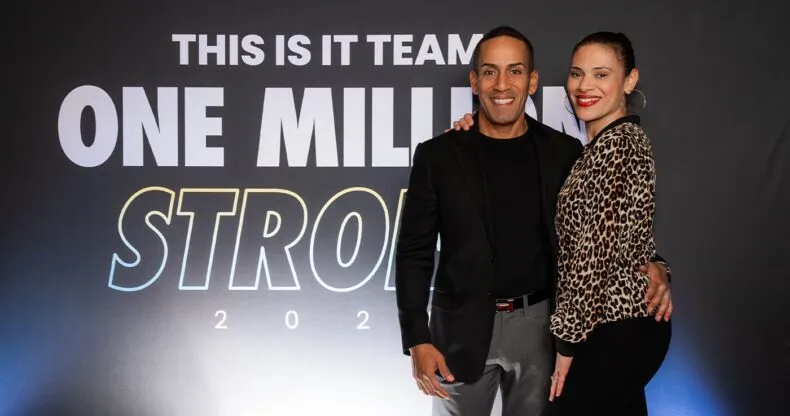 Mike and Sahi Hernandez smiling at the THIS IS IT Team One Million Strong event backdrop