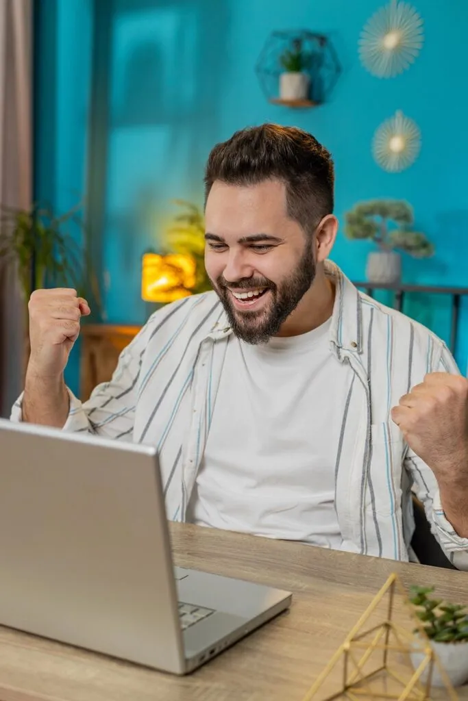 Entrepreneur celebrating online business success while working on laptop