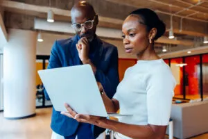 Business professionals reviewing information on a laptop during a mentoring discussion
