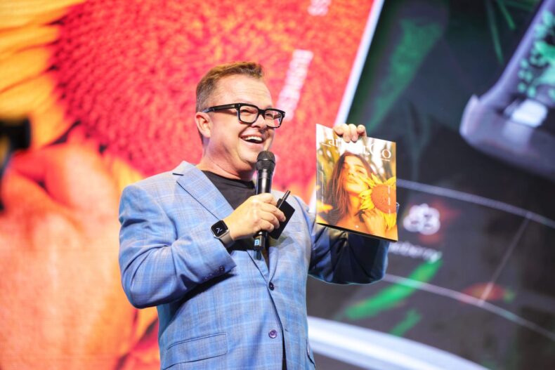 Partner.Co CMO Mark Patterson presenting at PXP event, holding magazine featuring Co.Lab products.