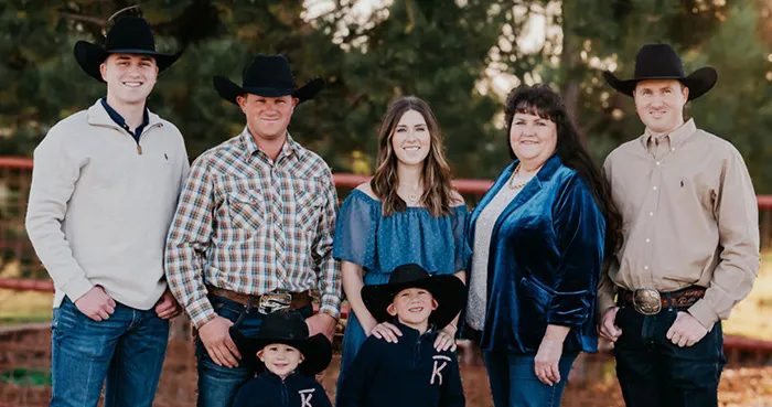 Penny Carpenter standing with her family on a ranch, all wearing western attire, showcasing their rural lifestyle.