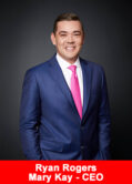 Ryan Rogers, CEO of Mary Kay, in a navy blue suit and pink tie, standing in front of a black background.