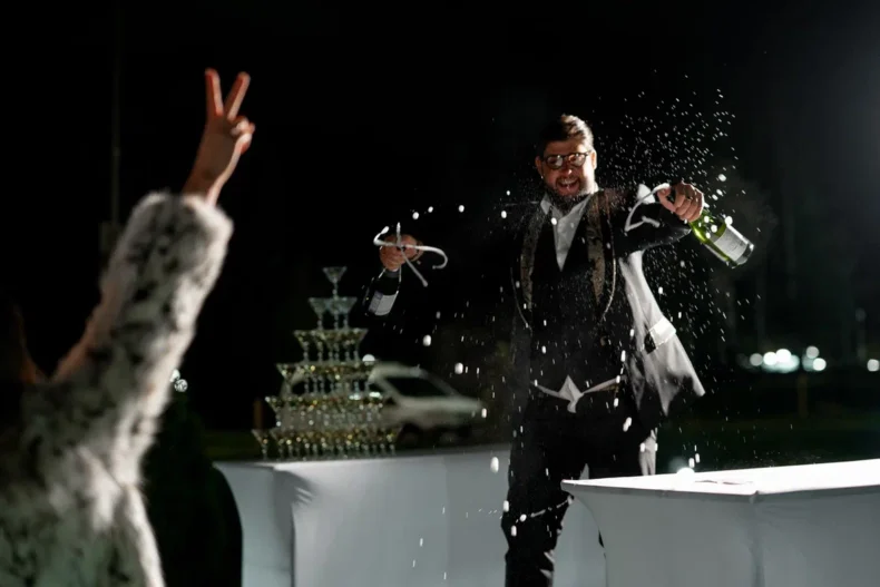 Sergey Kulikov celebrates APLGO’s 20th anniversary with champagne at a festive event.