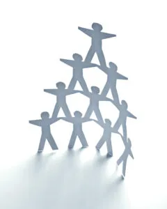 Paper cutout people forming a teamwork pyramid