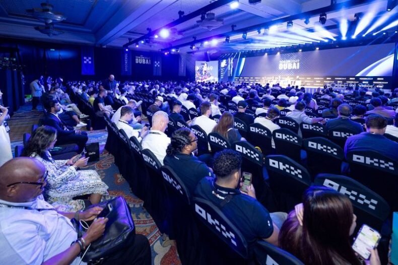 Audience seated at TOKEN2049 main keynote session in Dubai, watching the panel under purple lights