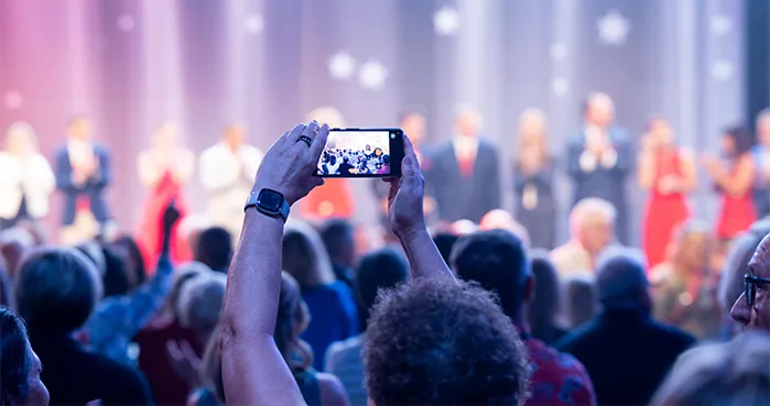 Attendee photographing a LifeWave recognition ceremony at UNSTOPPABLE Convention 2026