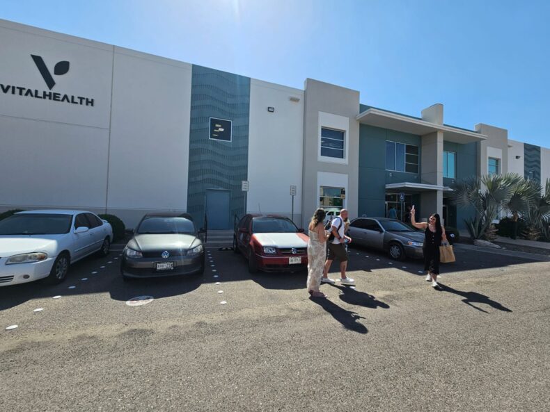 Exterior of the Vital Health Global building with people entering and parked cars in front.